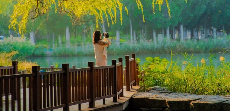 Frau steht am See, fotografiert die Natur und genießt die ruhige Umgebung