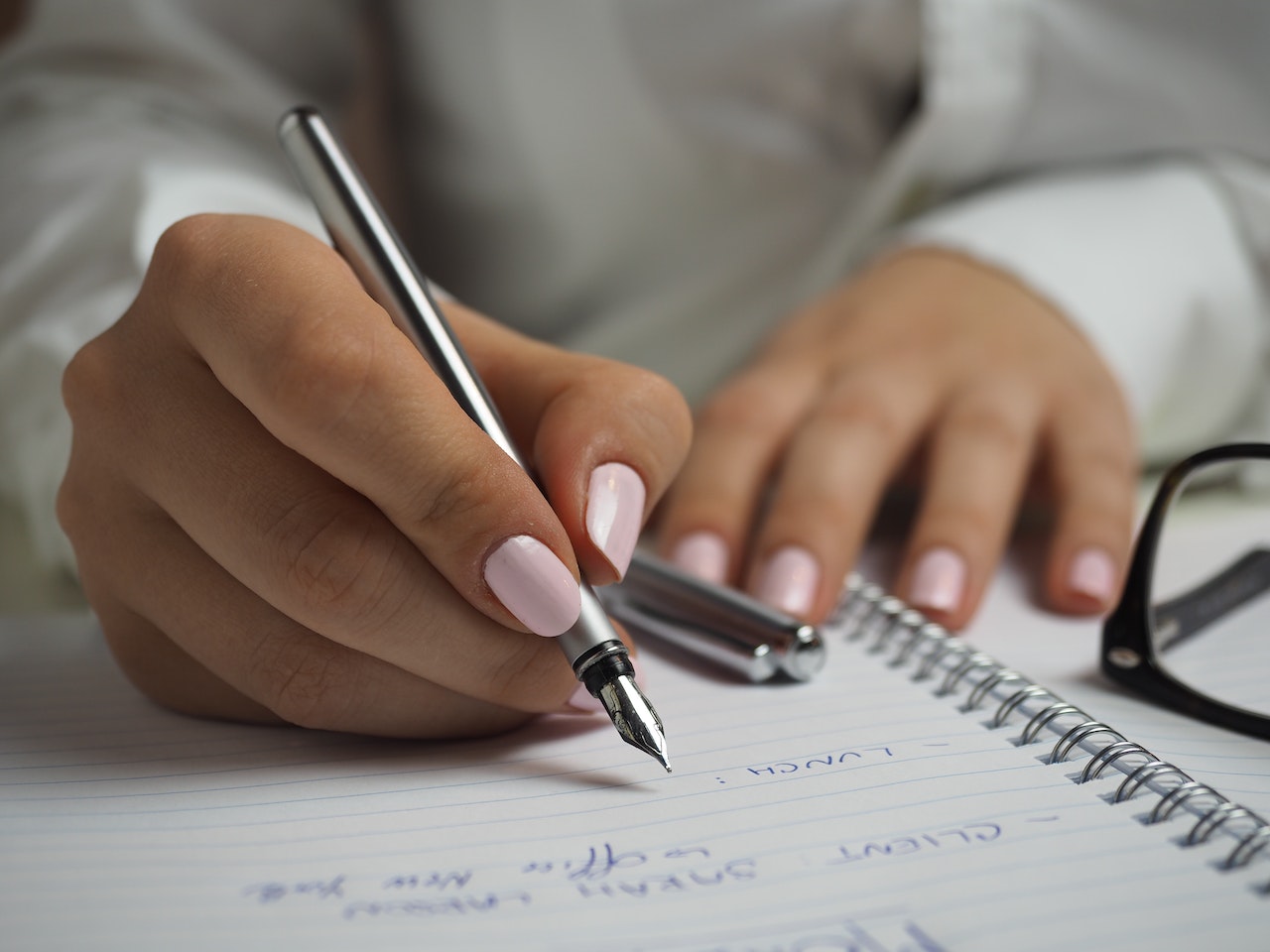 Frau, die mit einem Stift auf einem Block schreibt